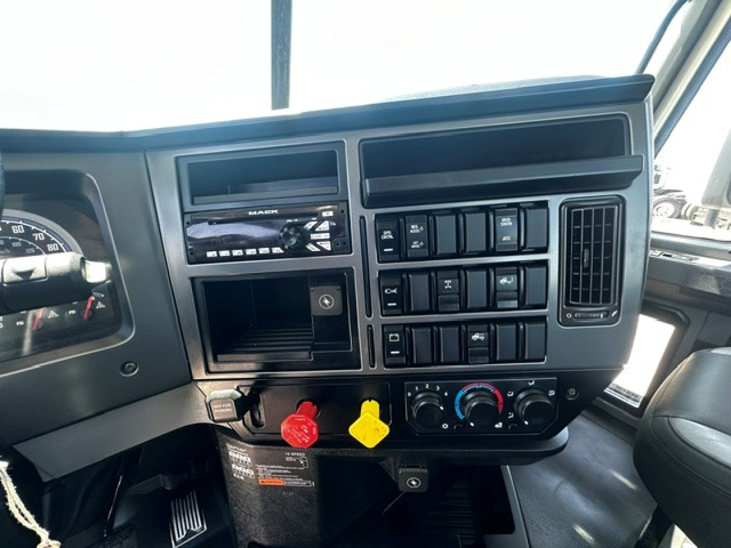 Mack PI64T truck cab dash area with control panel, climate controls, and ignition; visible labels include hazard/air switch and red/yellow keys.