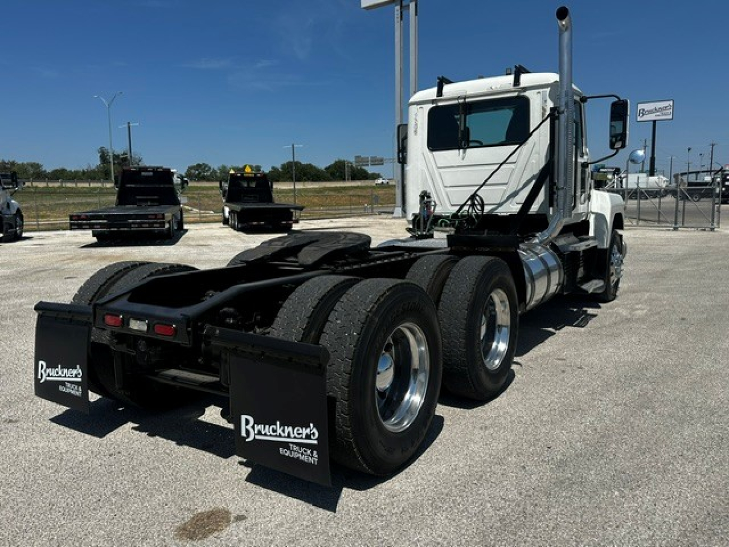 Mack PI64T conventional daycab tractor in profile showing rear axles and chassis with mud flaps and fuel tanks.