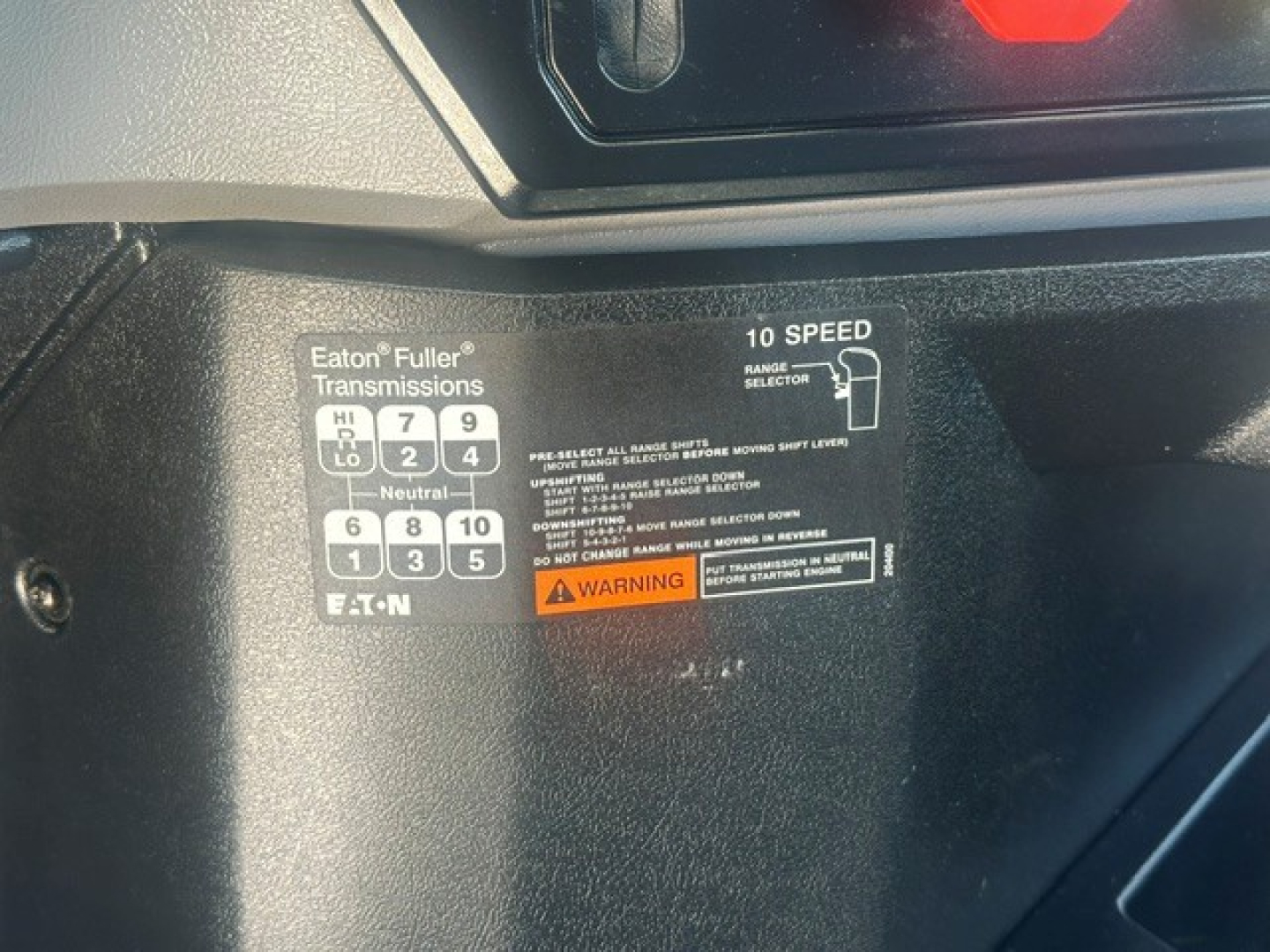 Vehicle cab interior label showing Eaton Fuller transmissions shifter pattern and 10 speed range selector with warning sticker.
