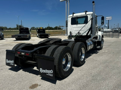 Mack PI64T conventional daycab tractor in profile showing rear axles and chassis with mud flaps and fuel tanks.