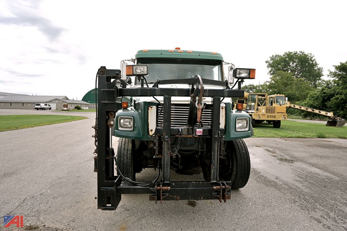 Front view of a green Freightliner FL70 dump/plow truck showing heavy duty front bumper and hydraulic equipment