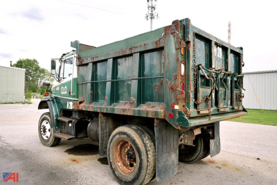 Forklift-style dump truck rear view showing green dump bed with rust accents and dual rear wheels