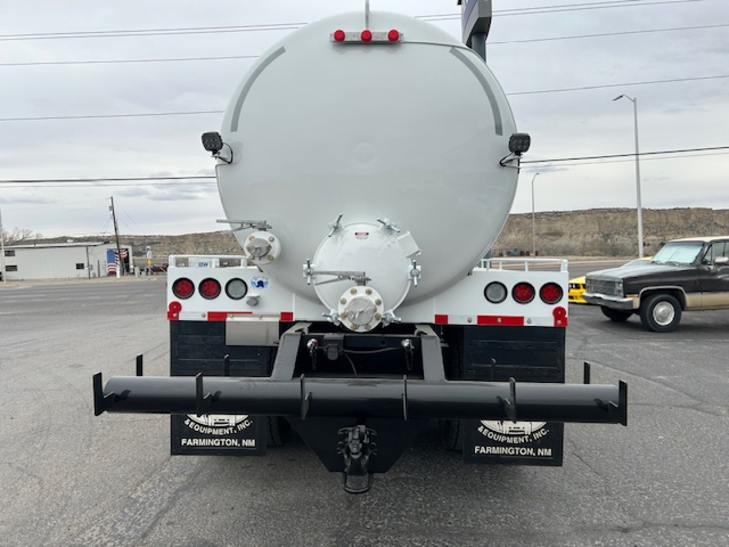 Rear view of a 2026 Mack GR64B vacuum tank truck showing rear bumper, taillights, and a circular tank with a rear hatch. Visible text on bumper area includes FARMINGTON, NM and equipment branding.