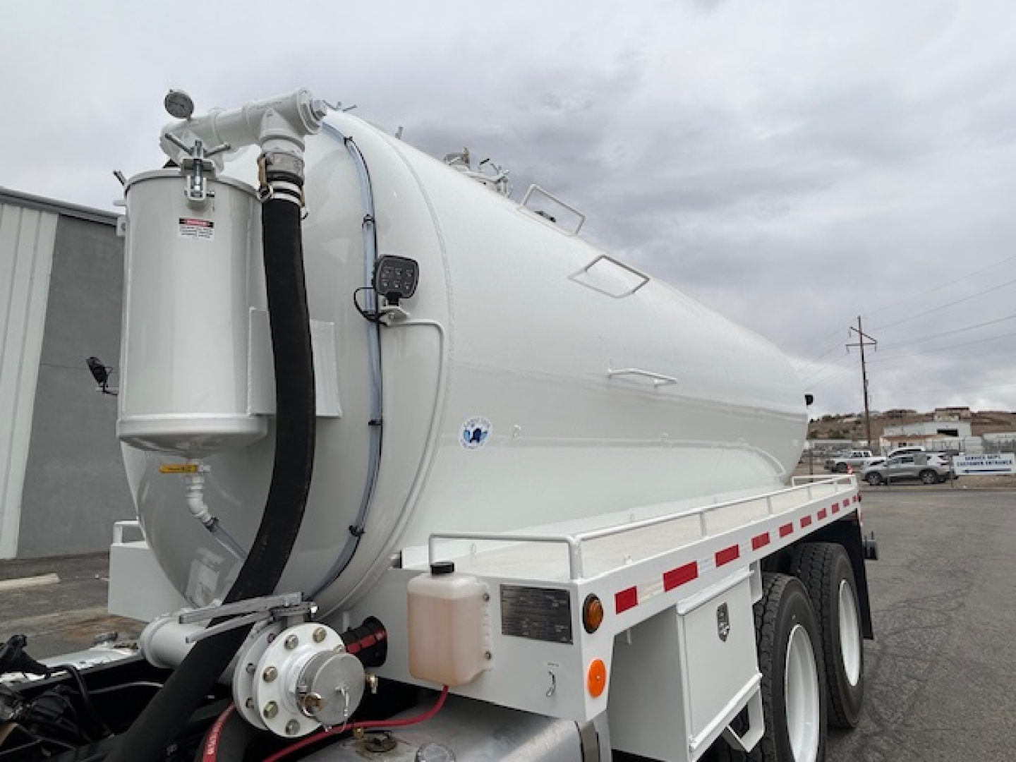 Mack GR64B vacuum tank truck in side view showing white cylindrical tank with hoses and controls on rear