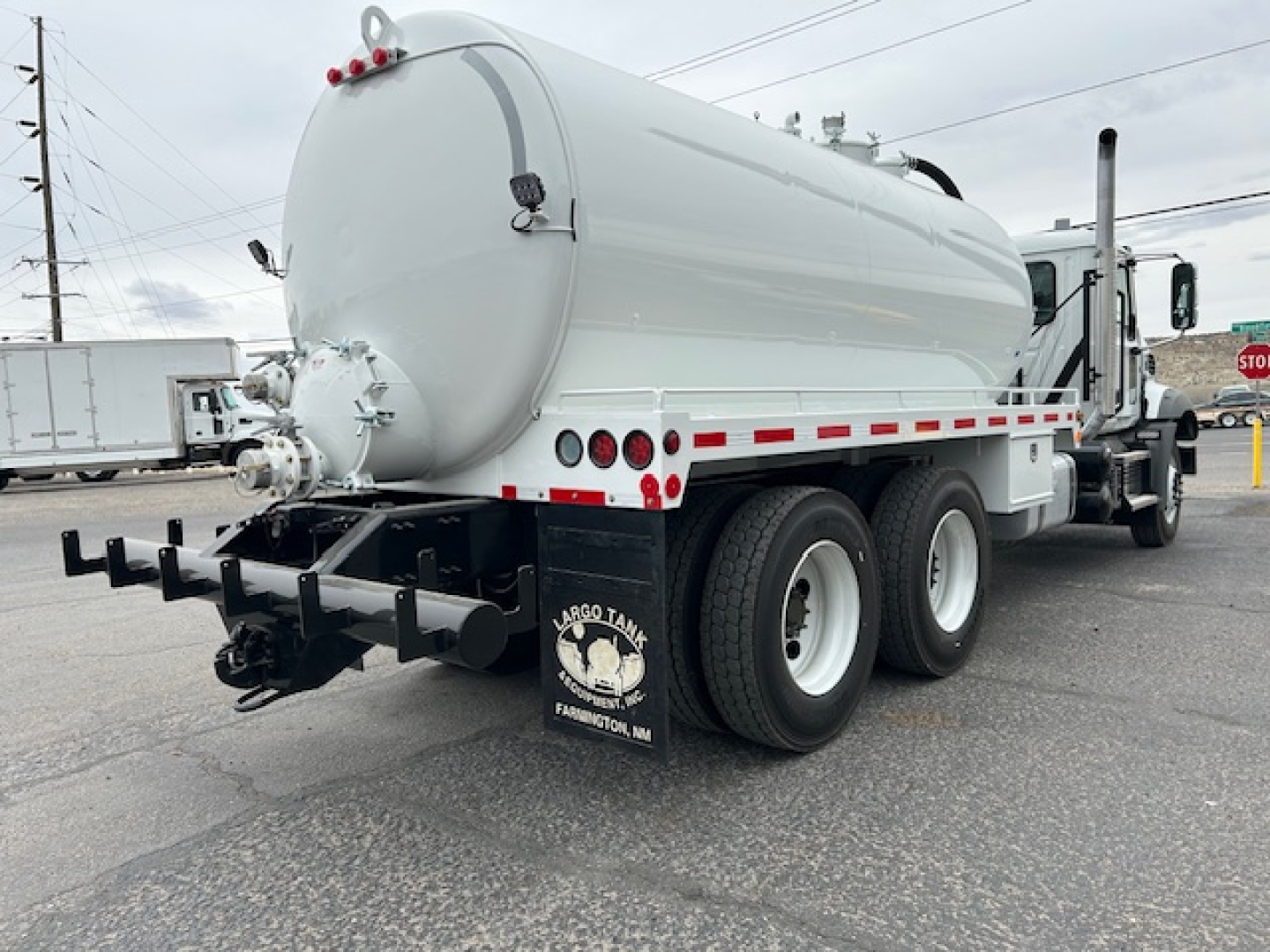Mack GR64B vacuum tank truck rear three-quarters view showing cylindrical tank with rear hoses and bumper.