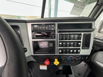Dashboard cockpit of a 2026 Mack GR64B truck showing control panel, switches, climate controls, and steering wheel; no visible text besides dashboard controls.