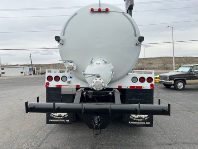 Rear view of a 2026 Mack GR64B vacuum tank truck showing rear bumper, taillights, and a circular tank with a rear hatch. Visible text on bumper area includes FARMINGTON, NM and equipment branding.