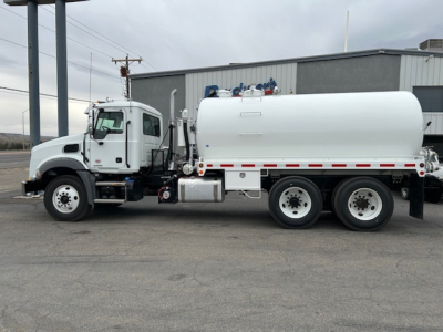 Truck side view of 2026 Mack GR64B vacuum tank, white cab and tank, three axles, fuel tank and vacuum hoses visible.