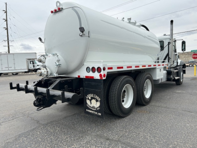 Mack GR64B vacuum tank truck rear three-quarters view showing cylindrical tank with rear hoses and bumper.