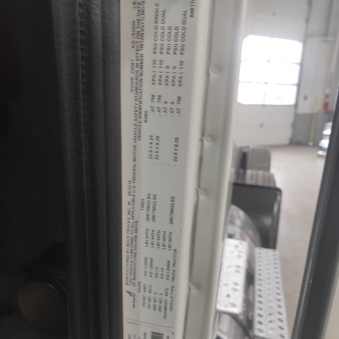 Truck cab door placard with specifications for a 2020 Mack AN64T showing tire and axle data, GAWR/GVWR-like numbers, and weight ratings visible as a vertical label.