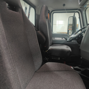 Truck cab interior showing driver seat and passenger seat with gray fabric, dashboard, steering wheel, and door panels in view.