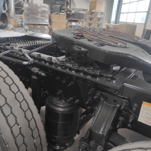 Tractor truck chassis showing air intake/air filter canister and drivetrain components near the rear wheel in a workshop.