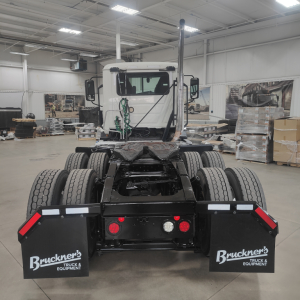 Truck rear view showing dual rear axles and Bruckner's mudflaps with white text on black backgrounds.