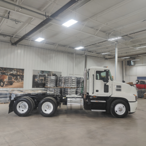 Truck chassis cab in a showroom with white cab and attached frame; no visible text noted on components.