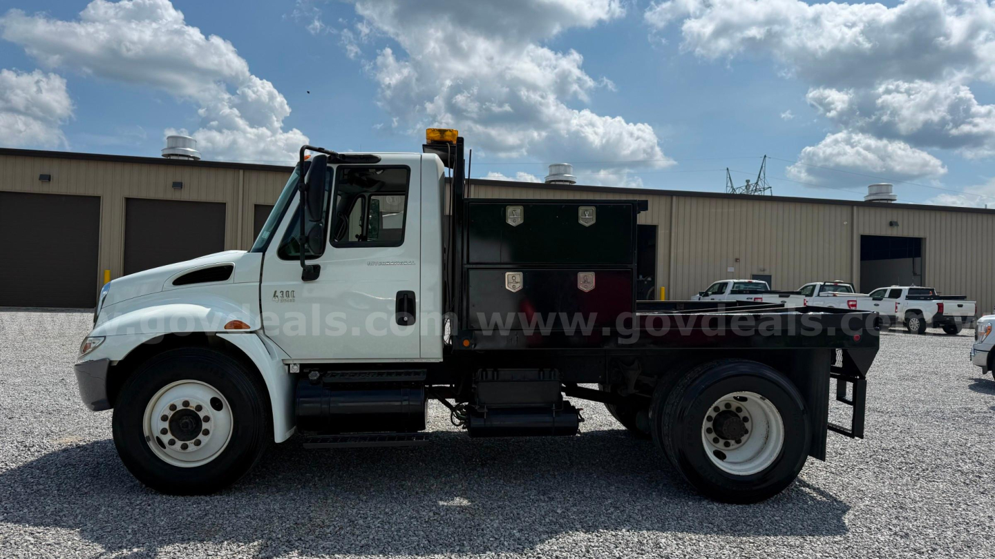 Truck cab and flatbed body side view with storage boxes on bed and International logo visible.