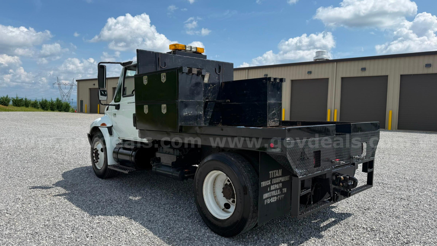 International 4300 flatbed tow truck chassis showing toolboxs and dual rear wheels.