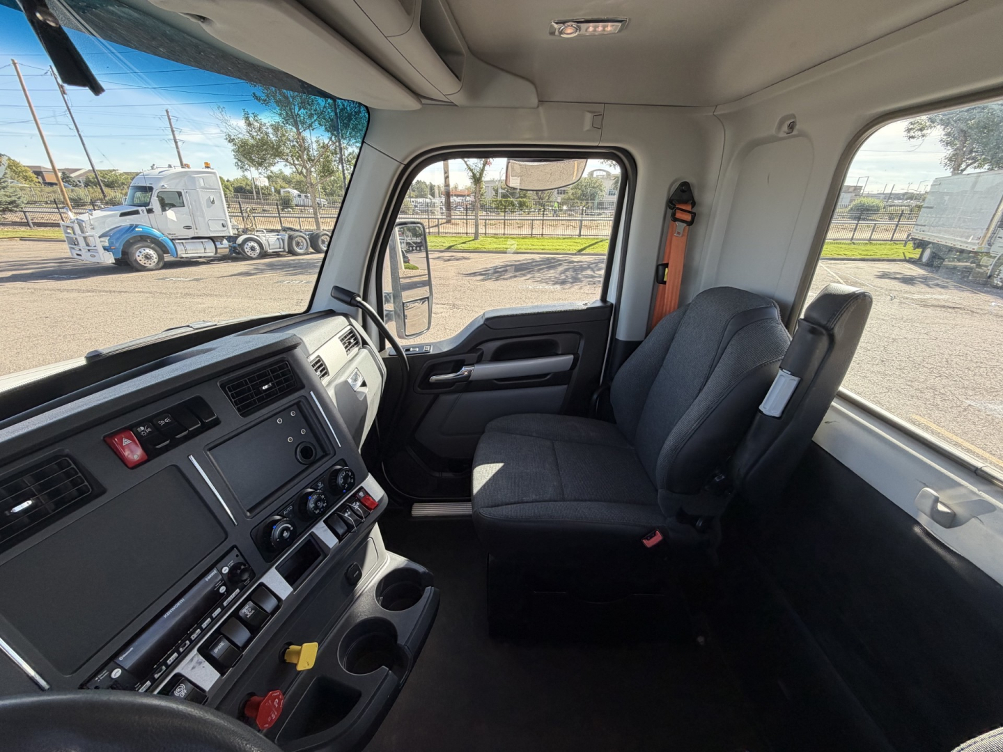 Kenworth T880 cab interior showing driver seat and dashboard with control panels and cup holders.