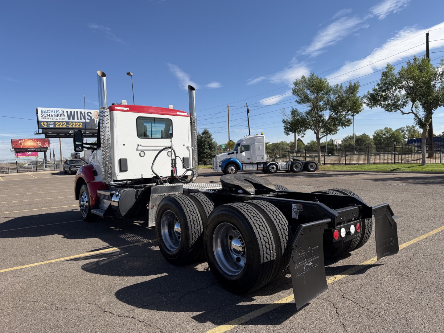Kenworth T880 conventional daycab truck chassis with dual rear axles in a parking lot, showing the rear wheelset and frame.