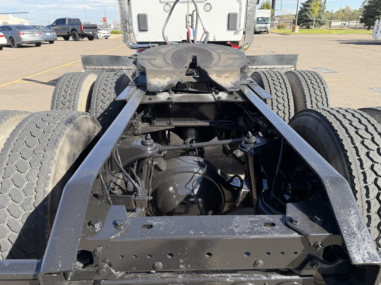 Kenworth T880 chassis rear view showing drivetrain and dual rear axles with fifth wheel mounting, undercarriage components visible.