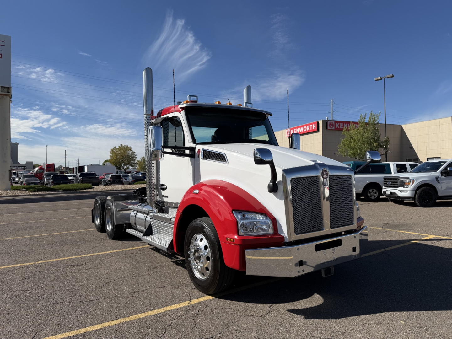 Kenworth T880 Conventional Daycab truck in a parking lot, front-side view, white cab with red fenders.