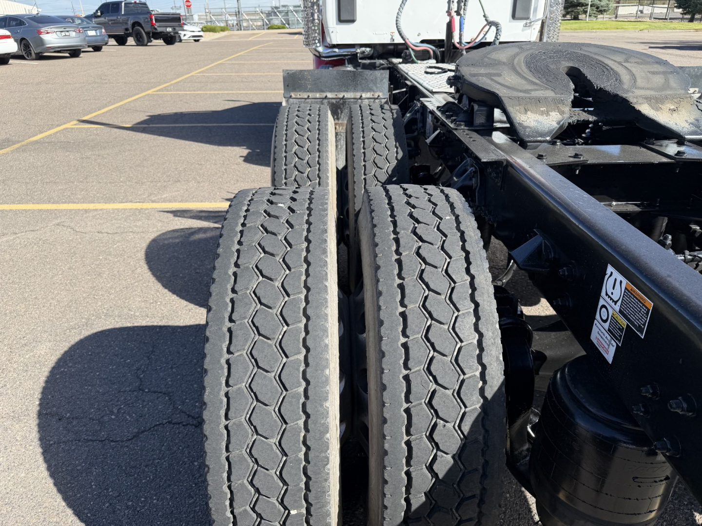 Kenworth T880 chassis with dual rear tires and fifth-wheel area visible, in a parking lot. Side view shows the back of the cab and drivetrain components.
