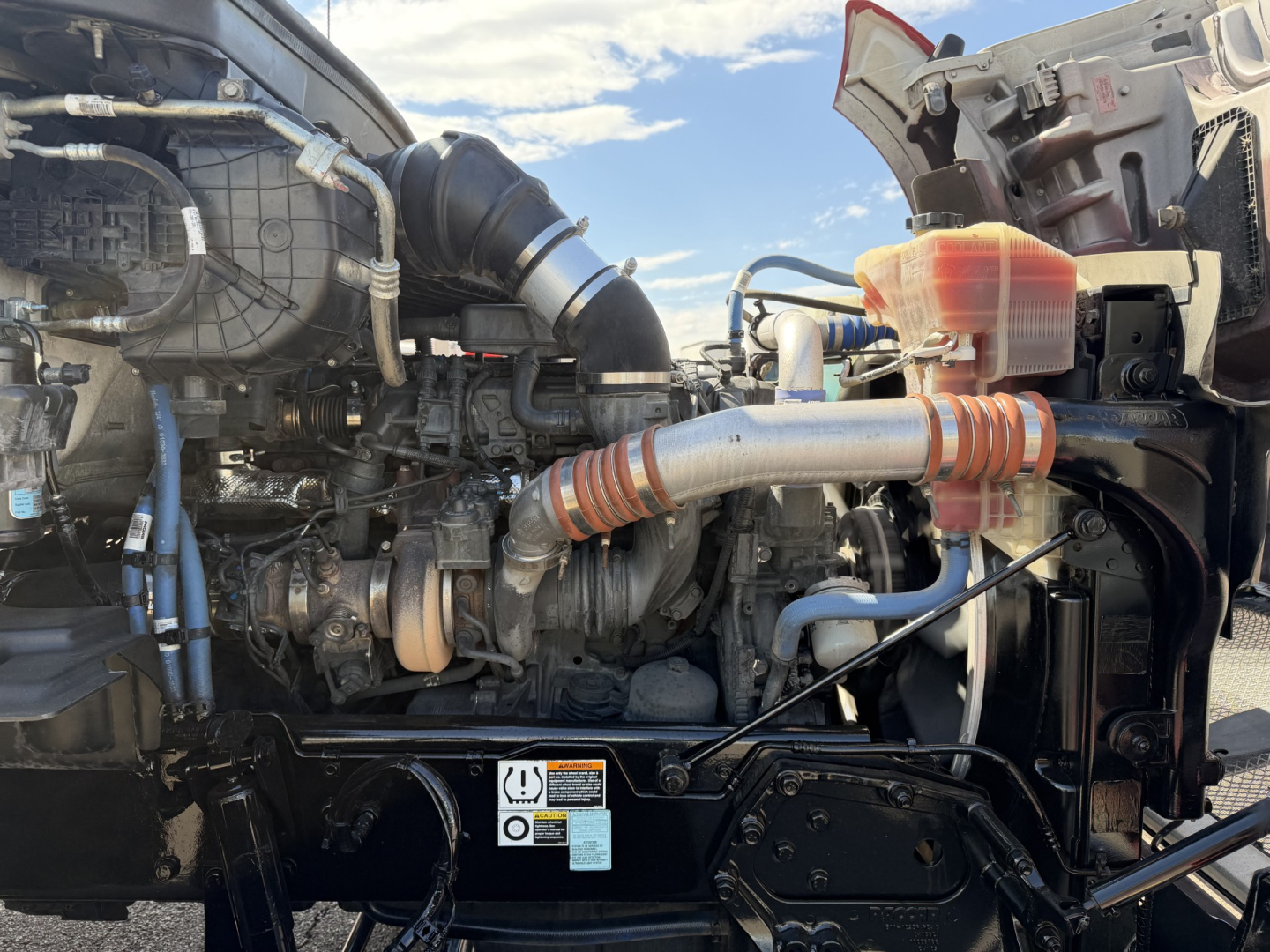 Kenworth T880 engine bay showing turbocharger, hoses, and radiator assembly with coolant reservoir and wiring harness.