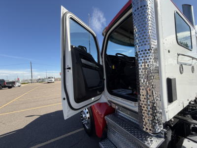 Kenworth T880 cab in-view showing open driver door and steps with metal diamond plate, chrome exhaust stack, and exterior chrome trim.