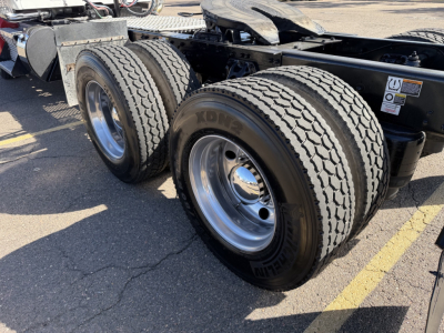 Kenworth T880 chassis showing dual rear axles with new tires and chrome wheels.