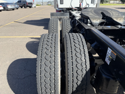 Kenworth T880 chassis with dual rear tires and fifth-wheel area visible, in a parking lot. Side view shows the back of the cab and drivetrain components.