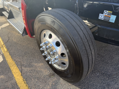Kenworth T880 front wheel showing shiny chrome lug nuts and black tire.
