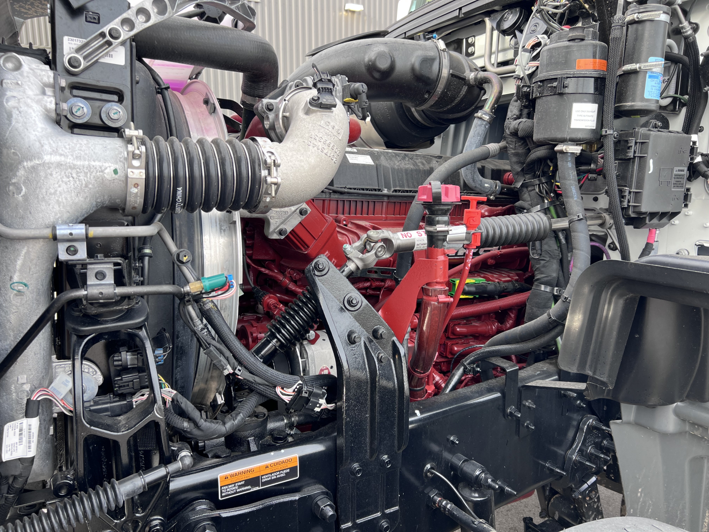 Mack GR64F truck engine bay showing high-visibility components, hoses, and red engine block.