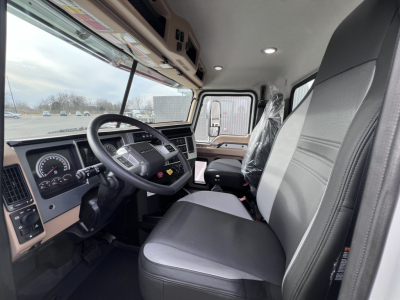 Truck cab interior of a 2026 Mack GR64F showing steering wheel, gauge cluster, and front seats from the driver's side.