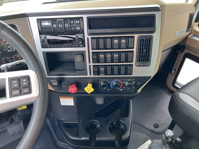 Dashboard view of a 2026 Mack GR64F truck showing gear selector, climate controls, multiple switches, and cup holders.