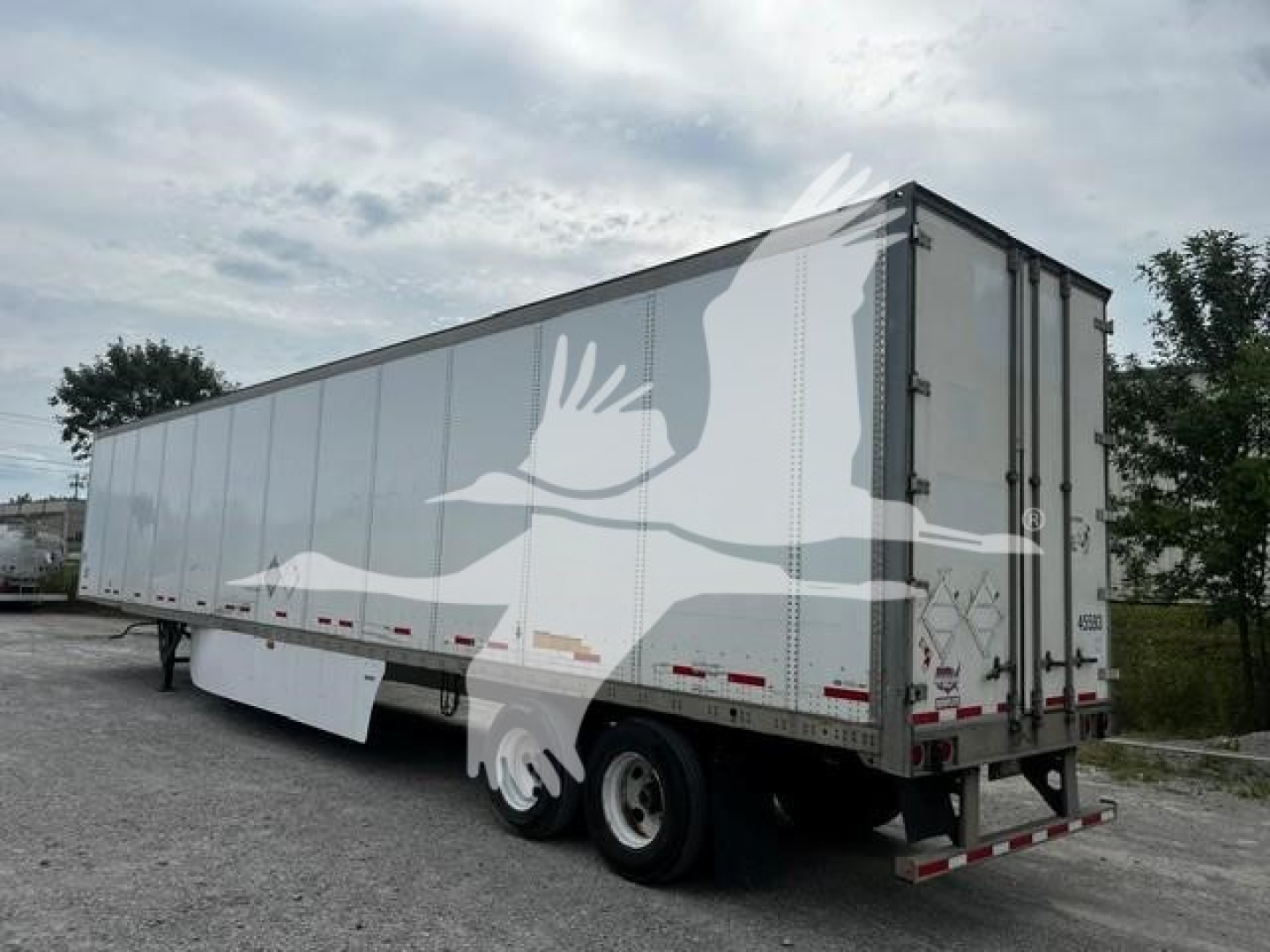 Trailer showing white Wabash dry van with dual rear doors, side reflectors, and tires under a gravel lot.