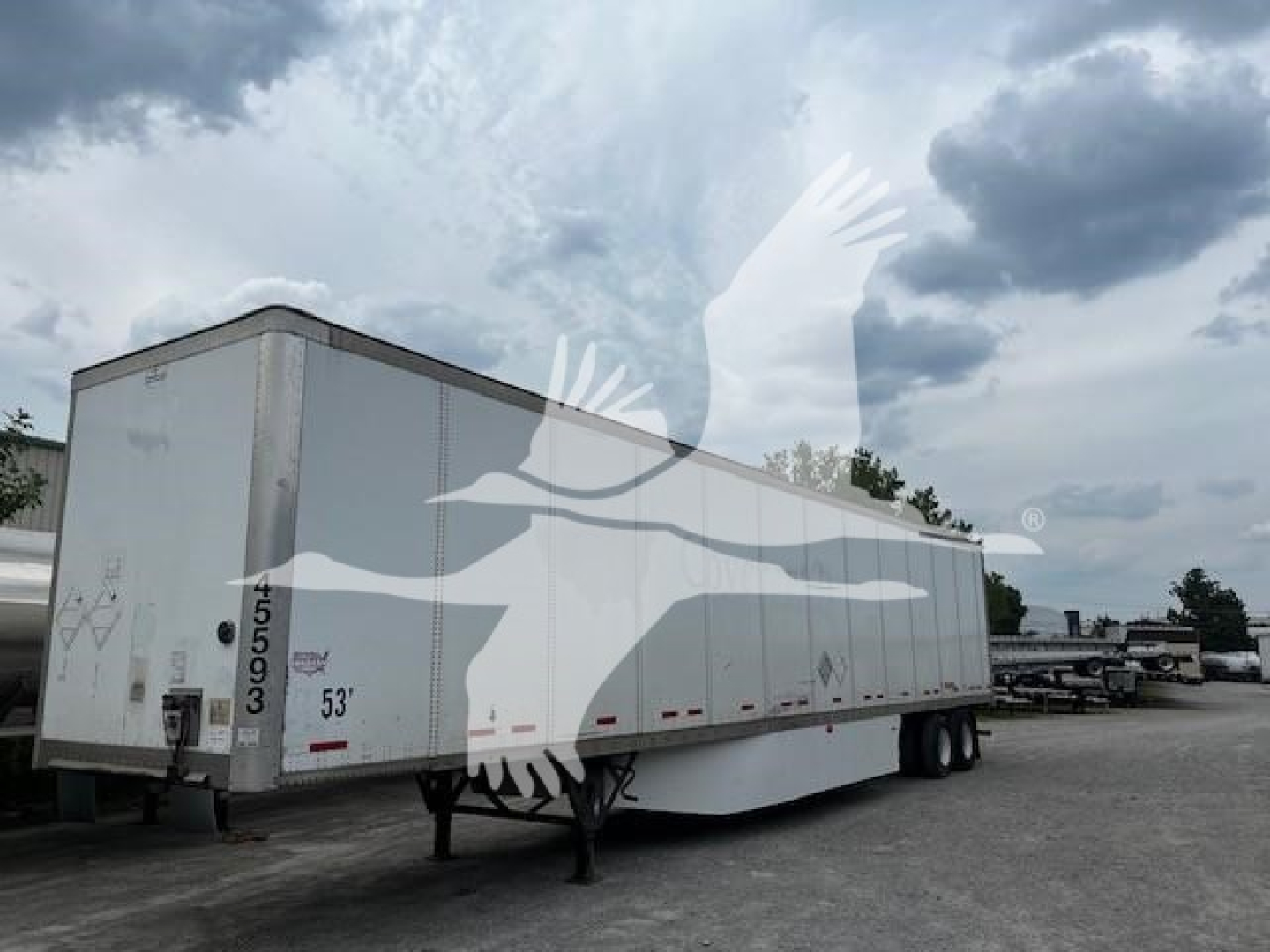 Trailer side view showing a white 53' dry van with Wabash branding watermark overlay; visible markings include 53', rear doors, and wheel area.