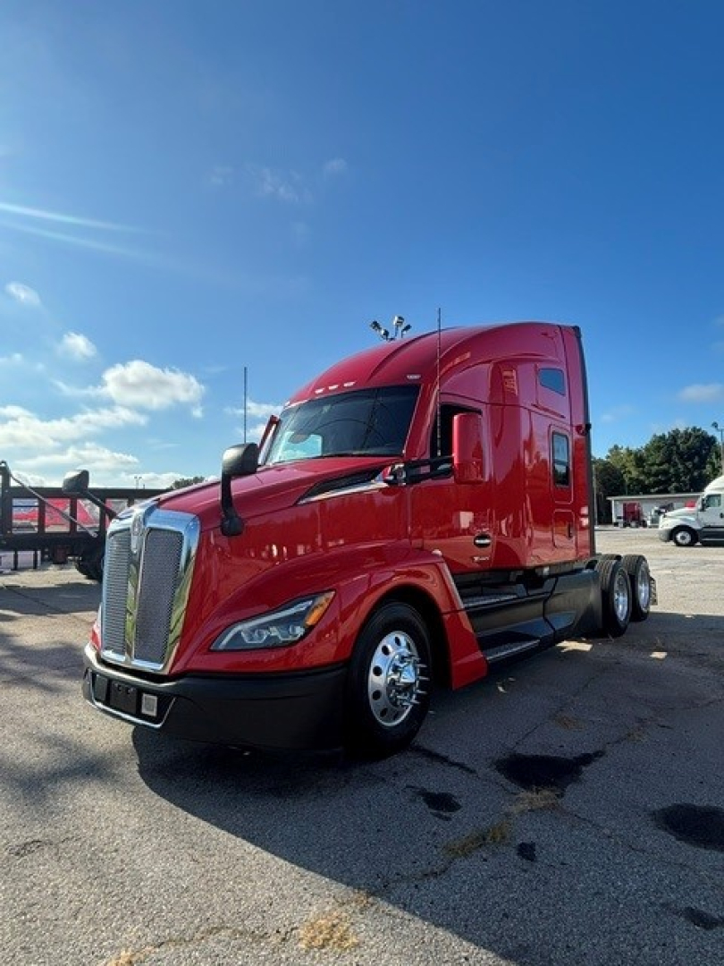 Kenworth T680 tractor in red, front three-quarter view, convention sleeper truck, chrome grille, dual rear axles, parked on lot.