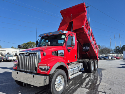 Western Star 47X dump truck with red cab and raised dump bed in a parking lot.