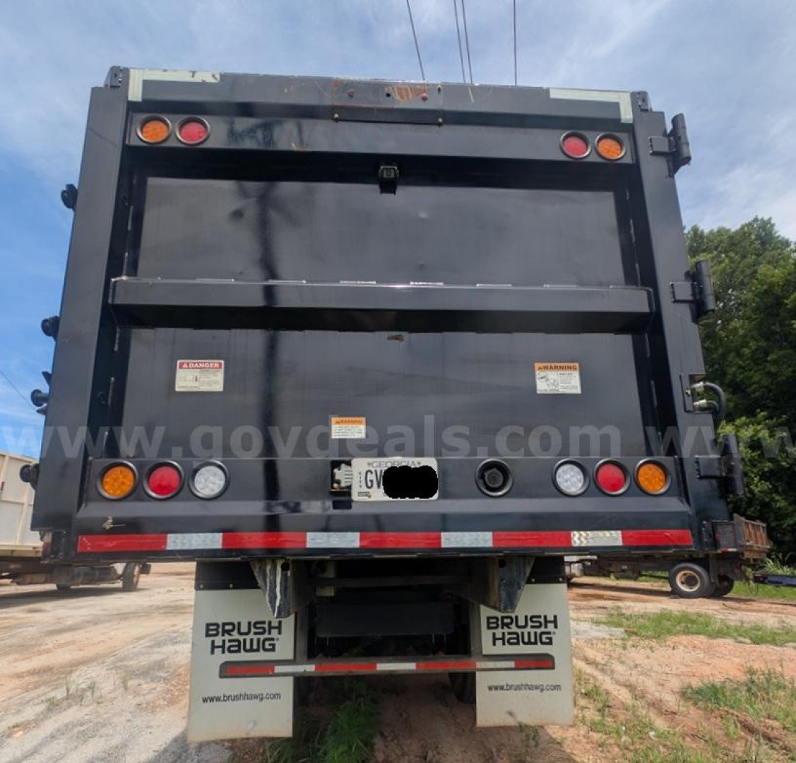 Back of a Mack MD dump truck with raised tailgate showing taillights and bumper.