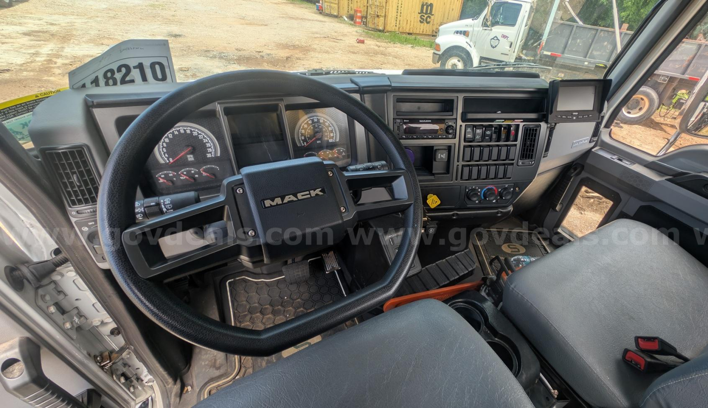 Mack truck interior dashboard and steering wheel with Mack logo visible, instrument cluster, control panel, and seats.