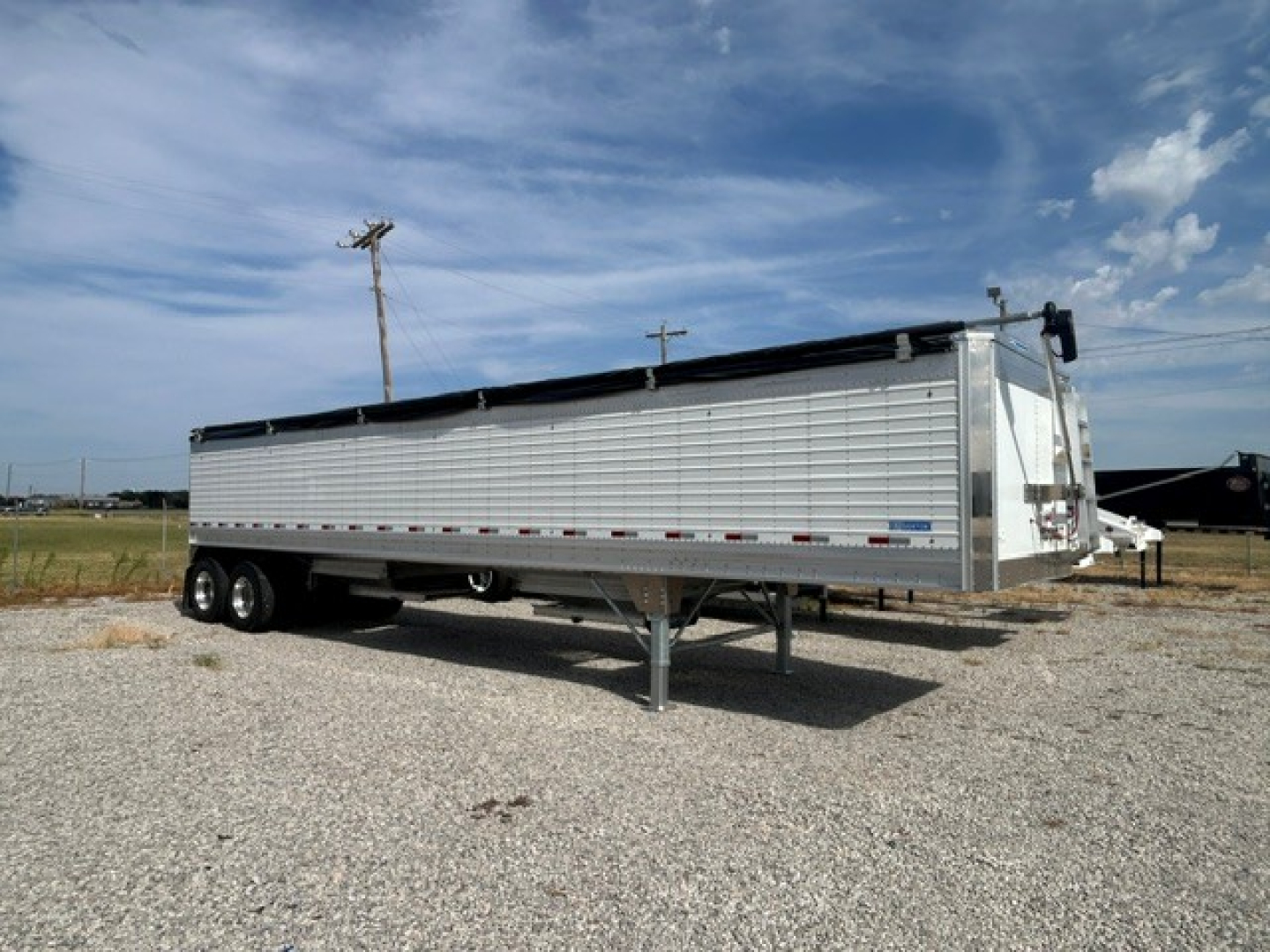 Stoughton 40' aluminum grain hopper trailer with 68" corrugated sidewalls and dual-axle configuration shown in a gravel lot.