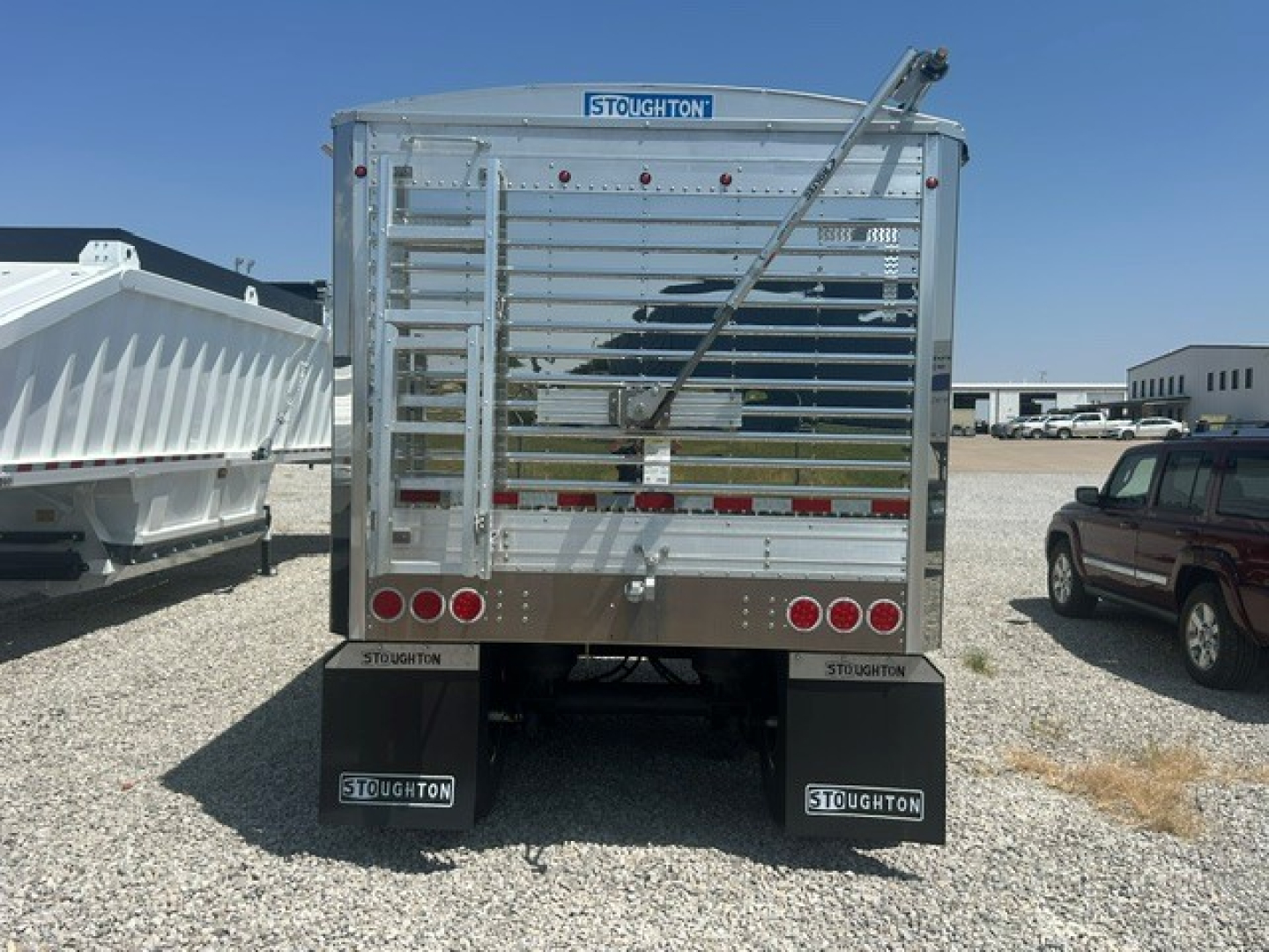 Trailers: rear view of 2027 Stoughton aluminum grain hopper trailer with corrugated 68-inch sidewalls, tailgate, and dual Stoughton mudflaps.