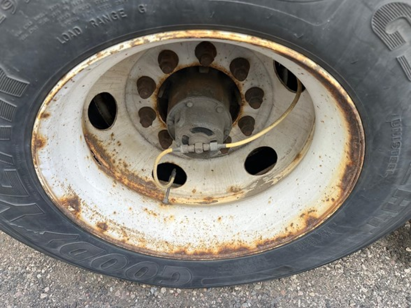 Wheel hub and tire with rusted steel rim on a Hyundai trailer axle.