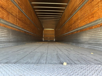 Hyundai air ride roll door dry van trailer interior revealing wooden sidewalls and metal floor; empty cargo area with tie rails along walls.