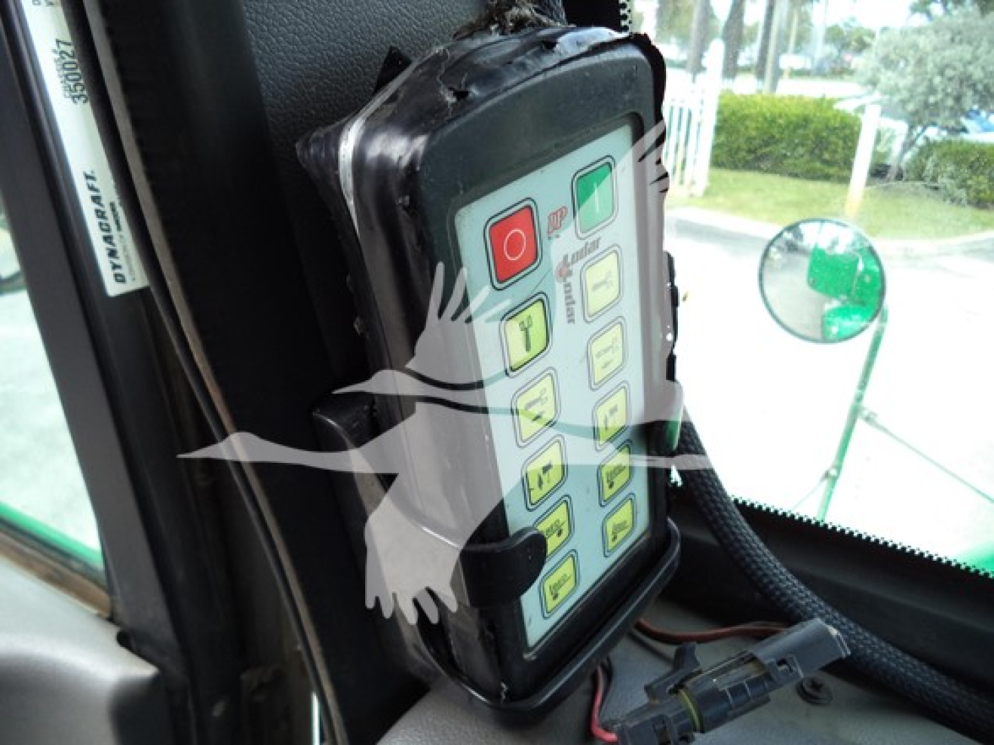 Dashboard control panel with colorful buttons inside a Peterbilt 348 cab, view through windshield and green side mirror.