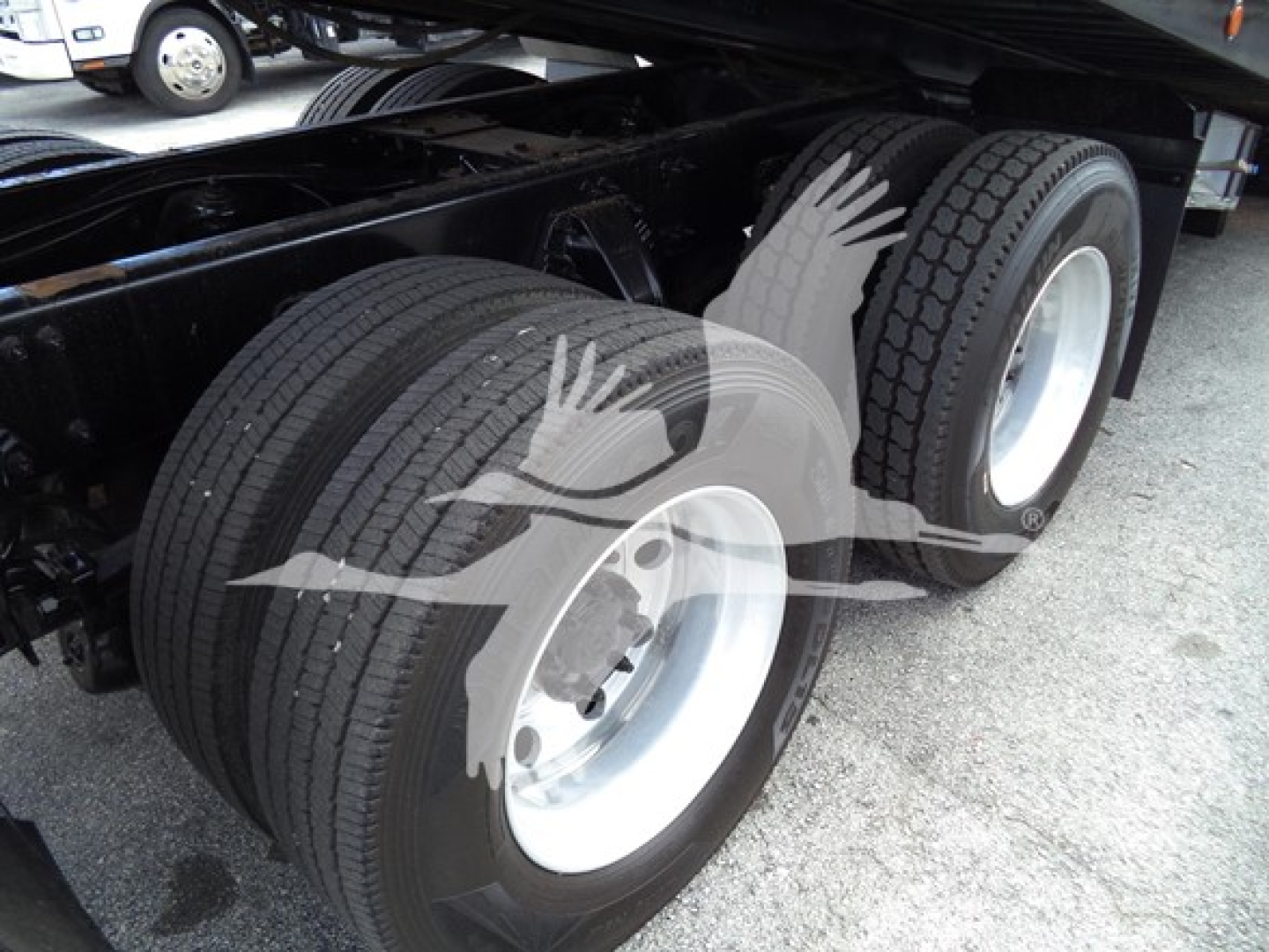 Peterbilt truck rear dual rear wheel setup with dual tires and white rims under a trailer frame. No visible text on components.