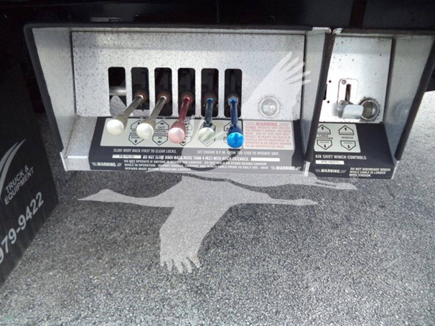 Tractor truck rear control panel showing multiple colored levers and warning labels.