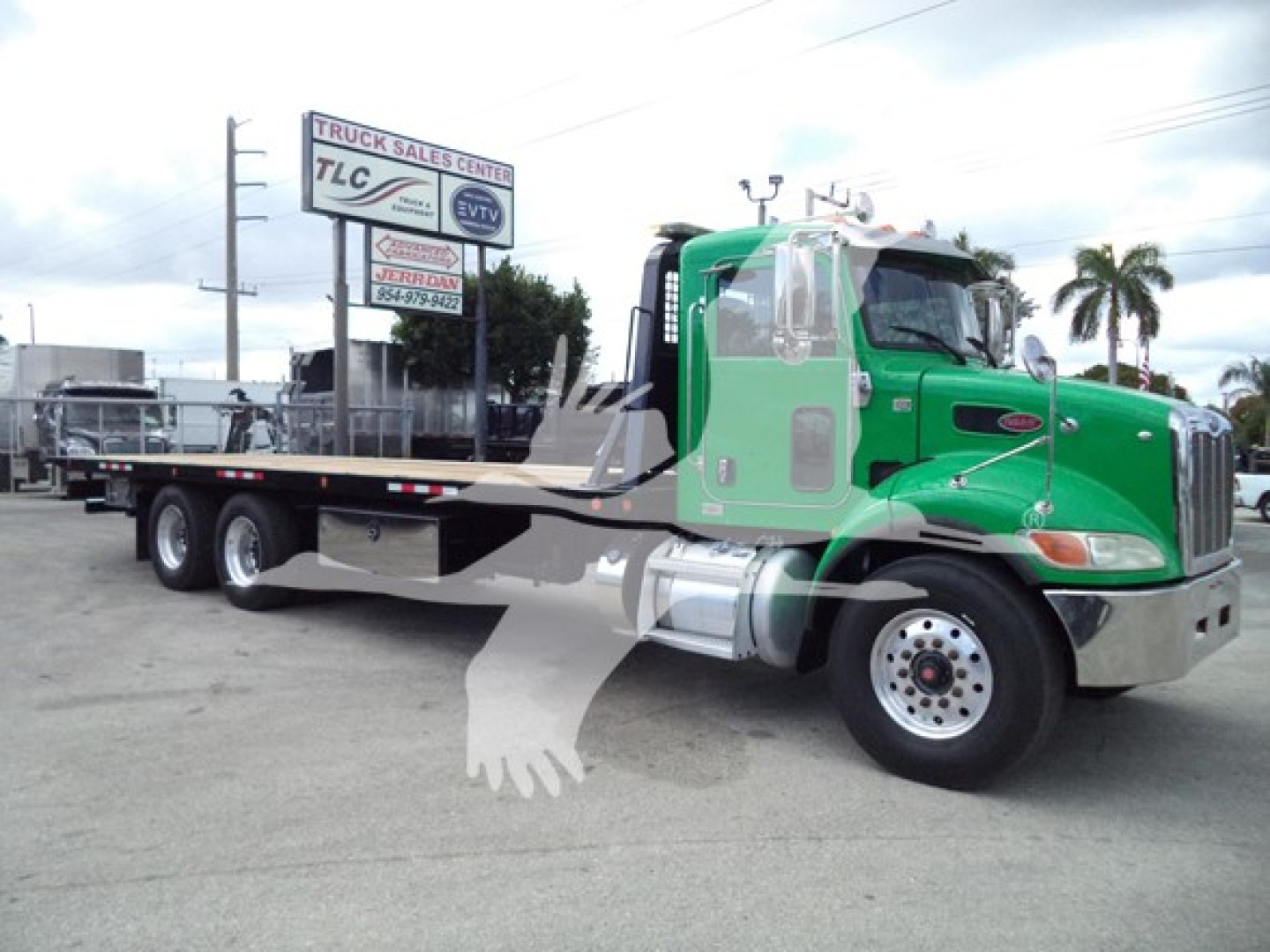 Peterbilt 348 rollback truck with green cab and long flatbed, side view, stock number T50027.