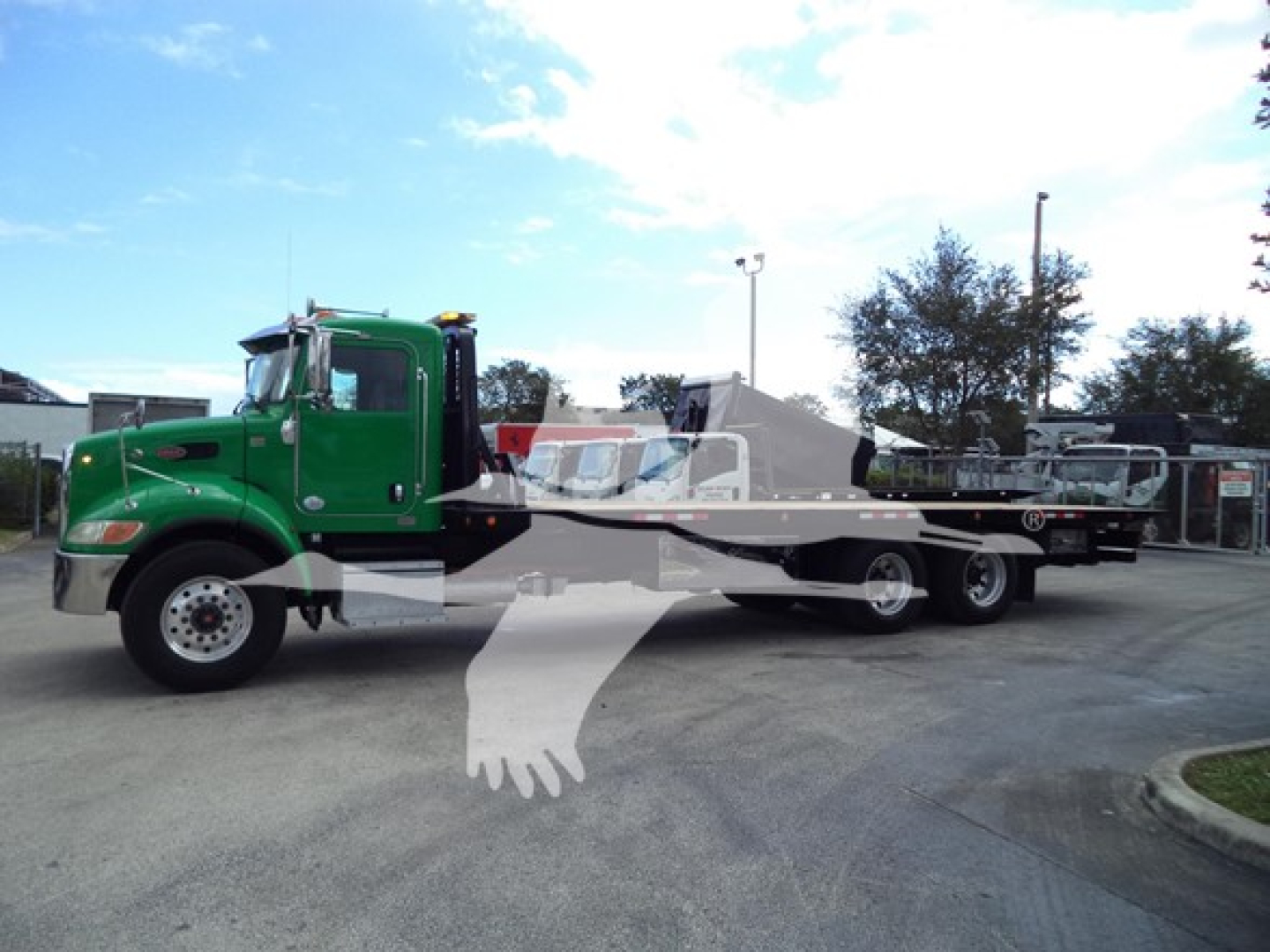 Peterbilt 348 rollback truck in green with flatbed and white written overlays.