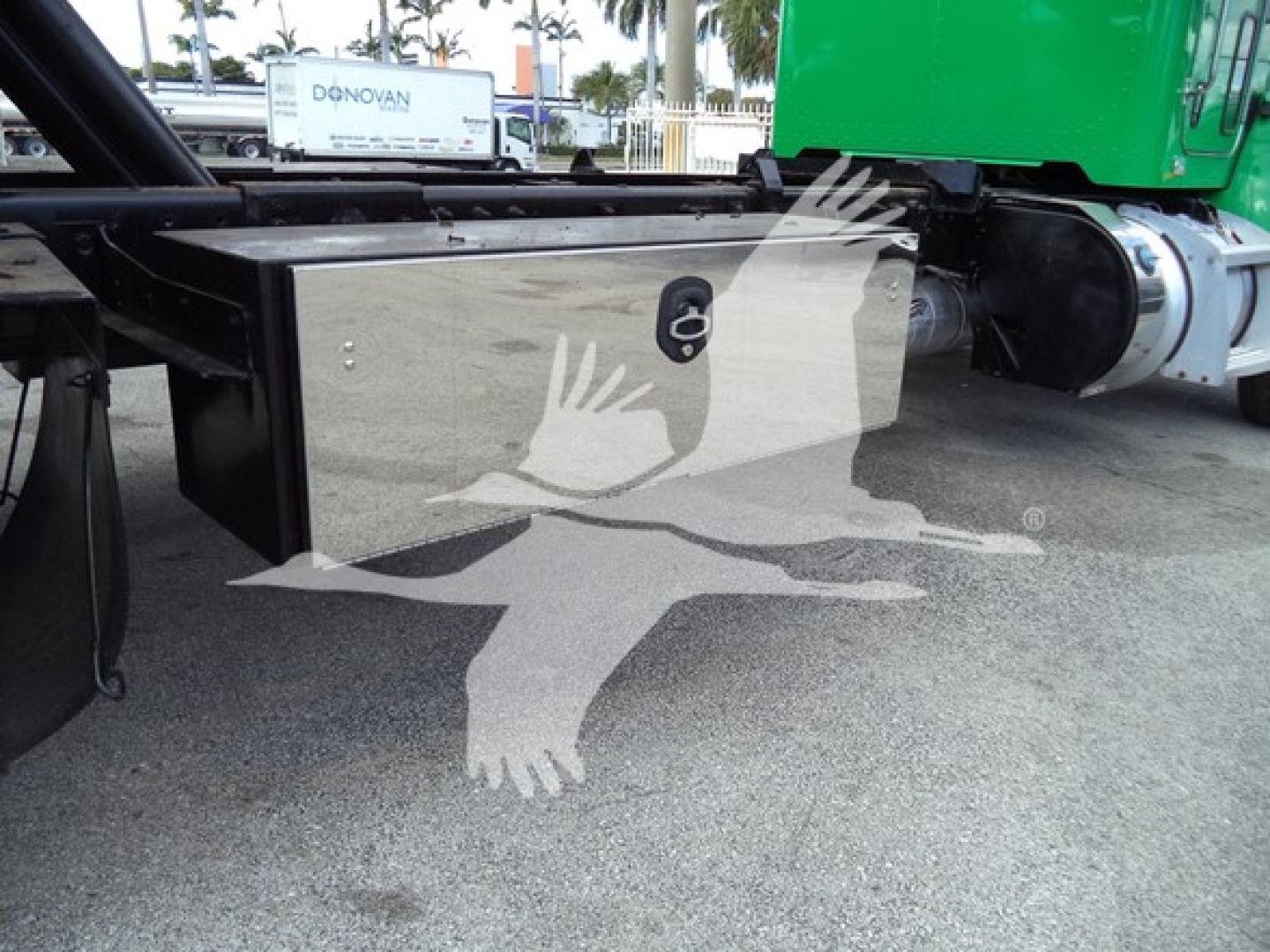 Peterbilt 348 rollback truck undercarriage showing black toolbox and hitch area with green cab visible in background.