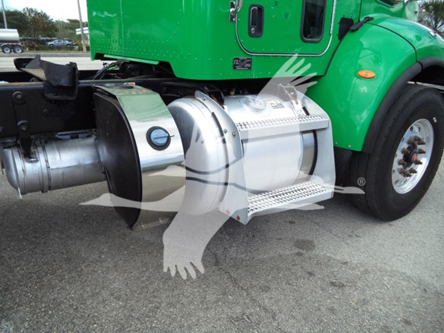 Peterbilt 348 truck side showing chrome fuel tanks and green cab, step and wheel well visible.